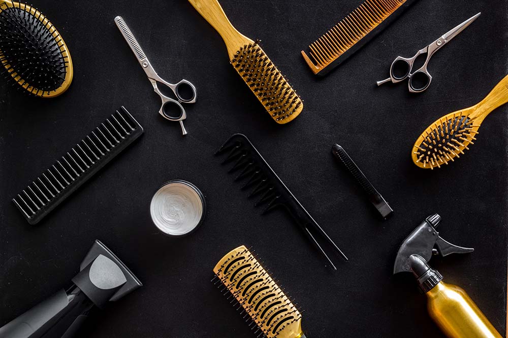 Hairdresser equipment for cutting hair and styling with combs, sciccors, brushes on black background top view pattern